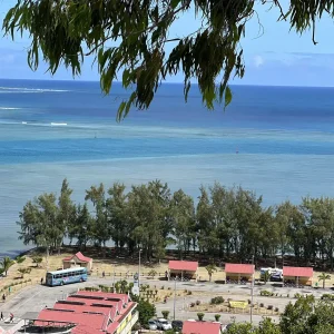 Coastal view of Rodrigues Island with red-roofed buildings, turquoise lagoon and casuarina trees