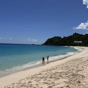 Pristine white sand beach with turquoise water and beachgoers in Seychelles