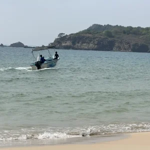Small speedboat near golden sand beach with rocky coastline at Trincomalee, Sri Lanka