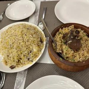 Traditional Kolkata biryani in earthenware handi and white plate at Indian restaurant - aromatic rice with meat