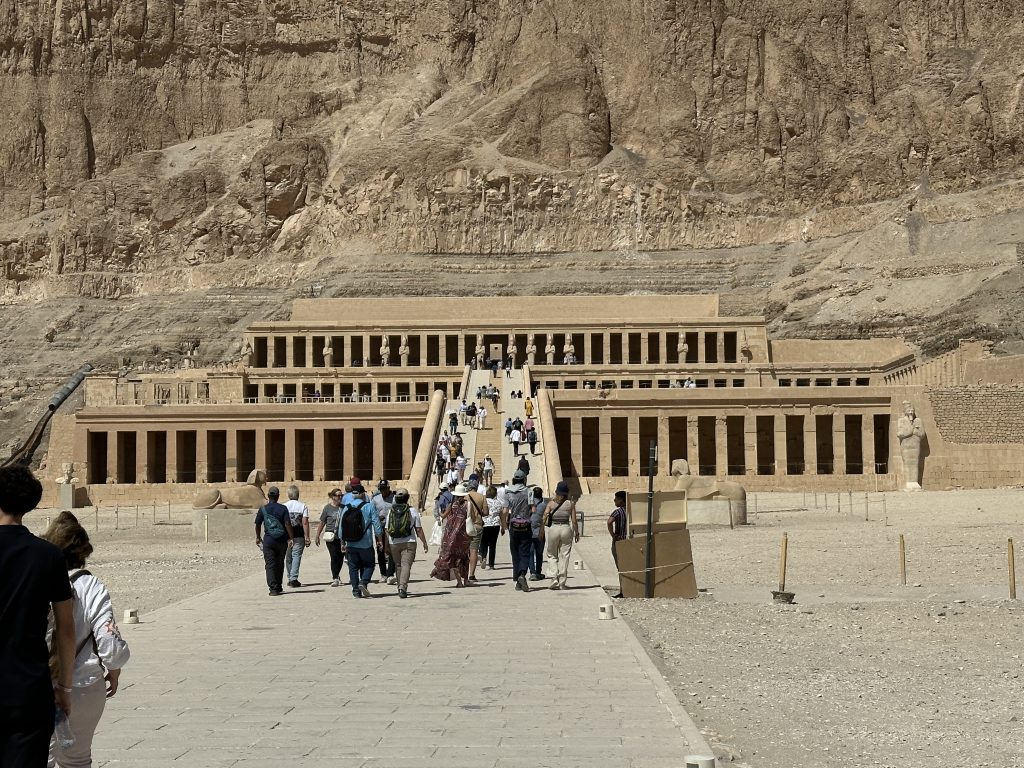 Visitors walking up the central ramp toward the terraced Mortuary Temple of Hatshepsut built into the cliffs on Luxor’s West Bank on Day 7 of a 10-Day Egypt Itinerary.