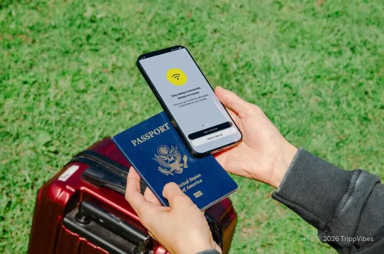 Phone showing an esim app beside a passport and suitcase, choosing the best esim for travel