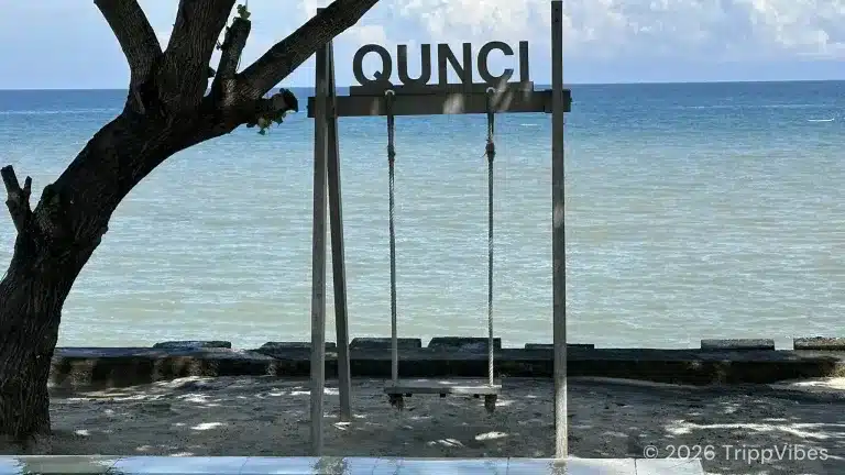 Wooden beach swing and qunci sign facing the sea at mangsit beach, from our qunci villas lombok hotel review